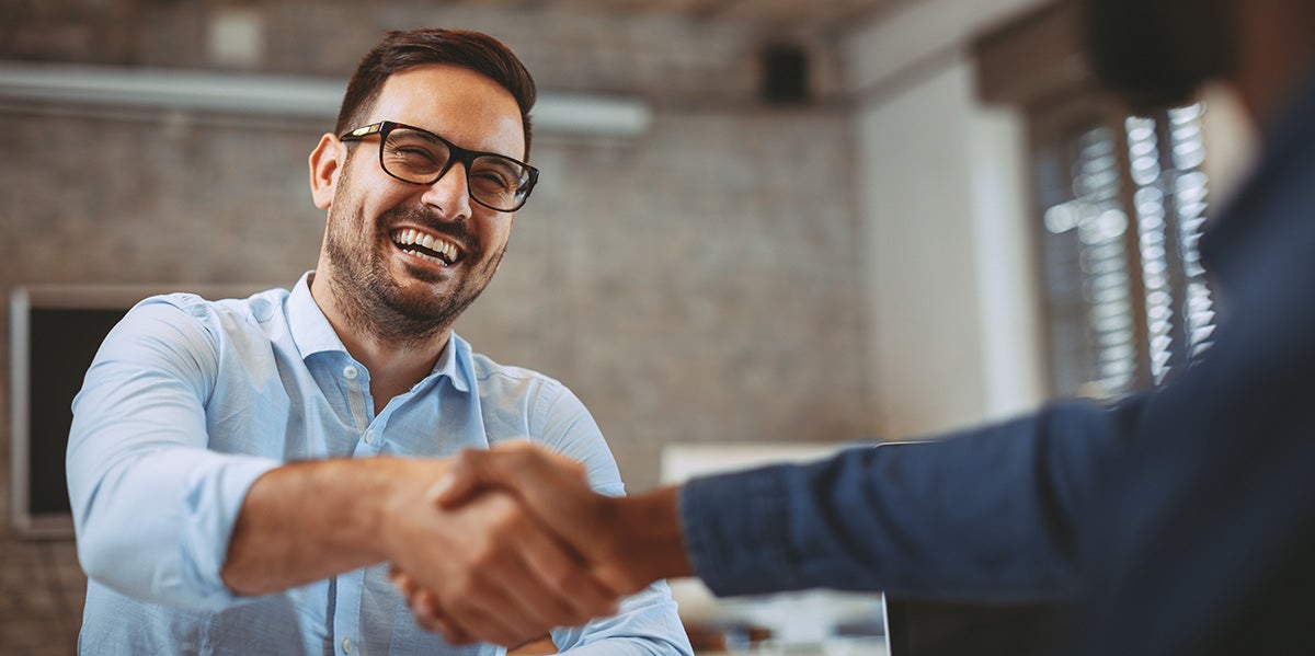 A smiling man shaking hands with a car dealer