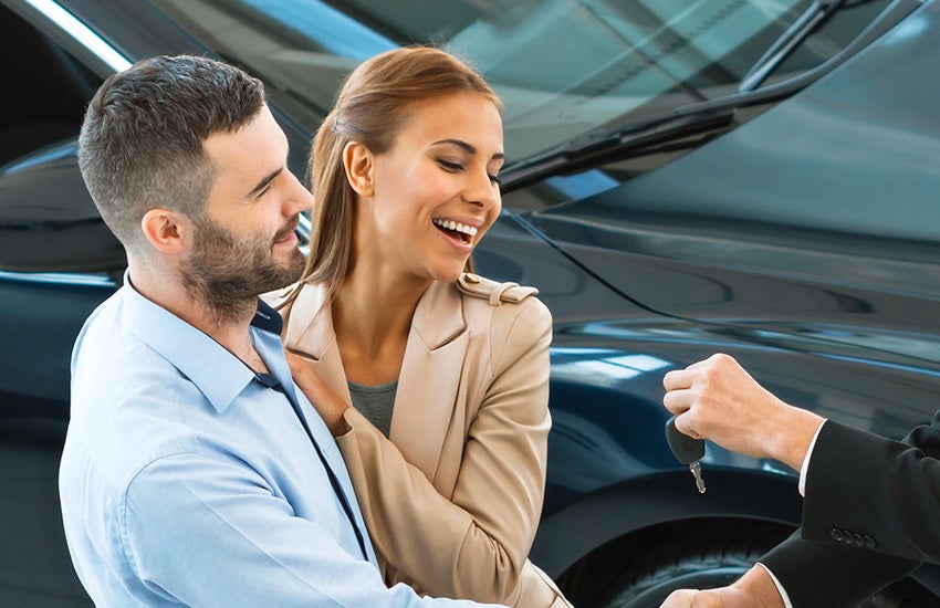 A man and woman receiving keys to a new car