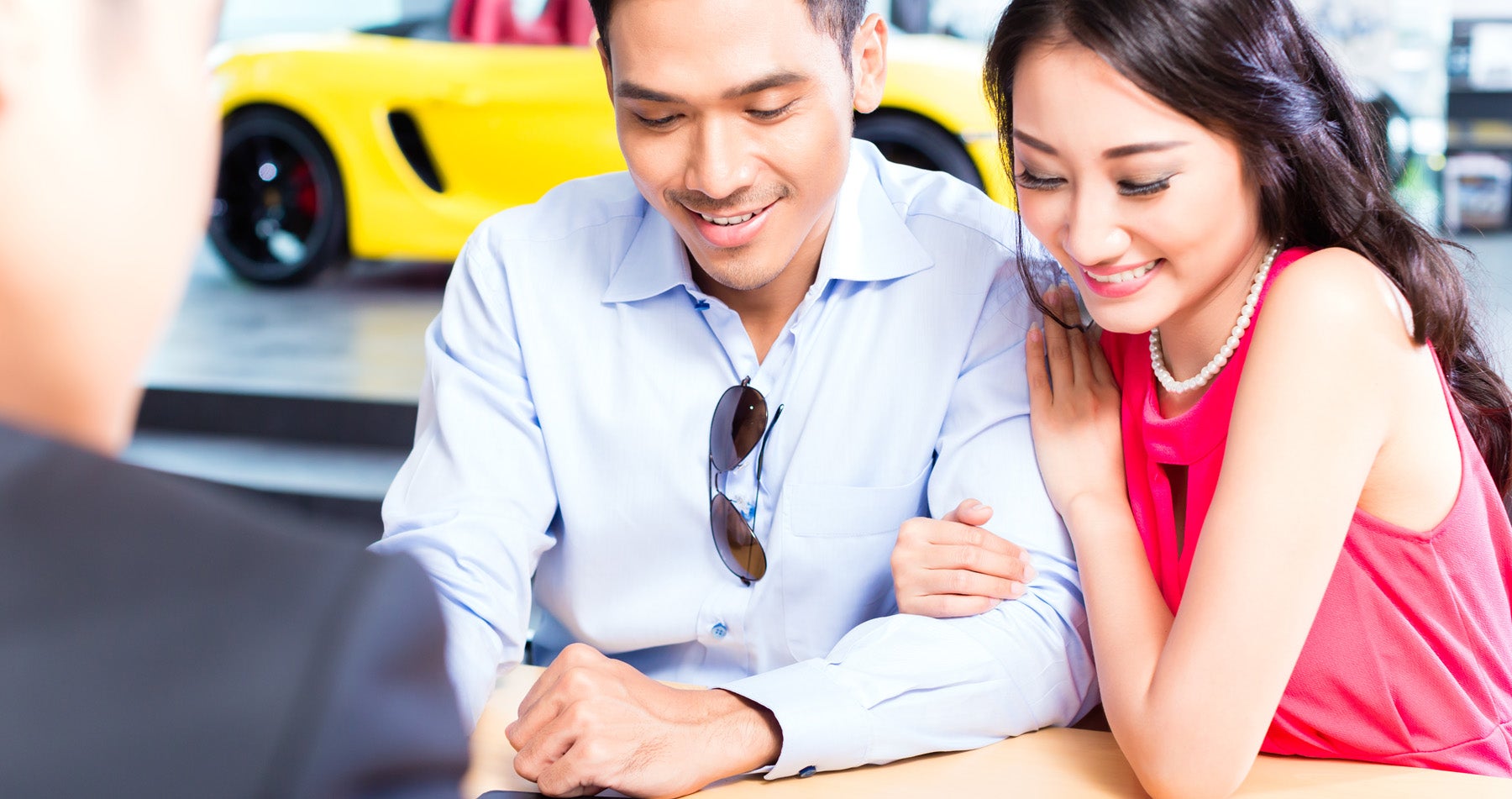A smiling man and woman going over paperwork at a dealership finance office