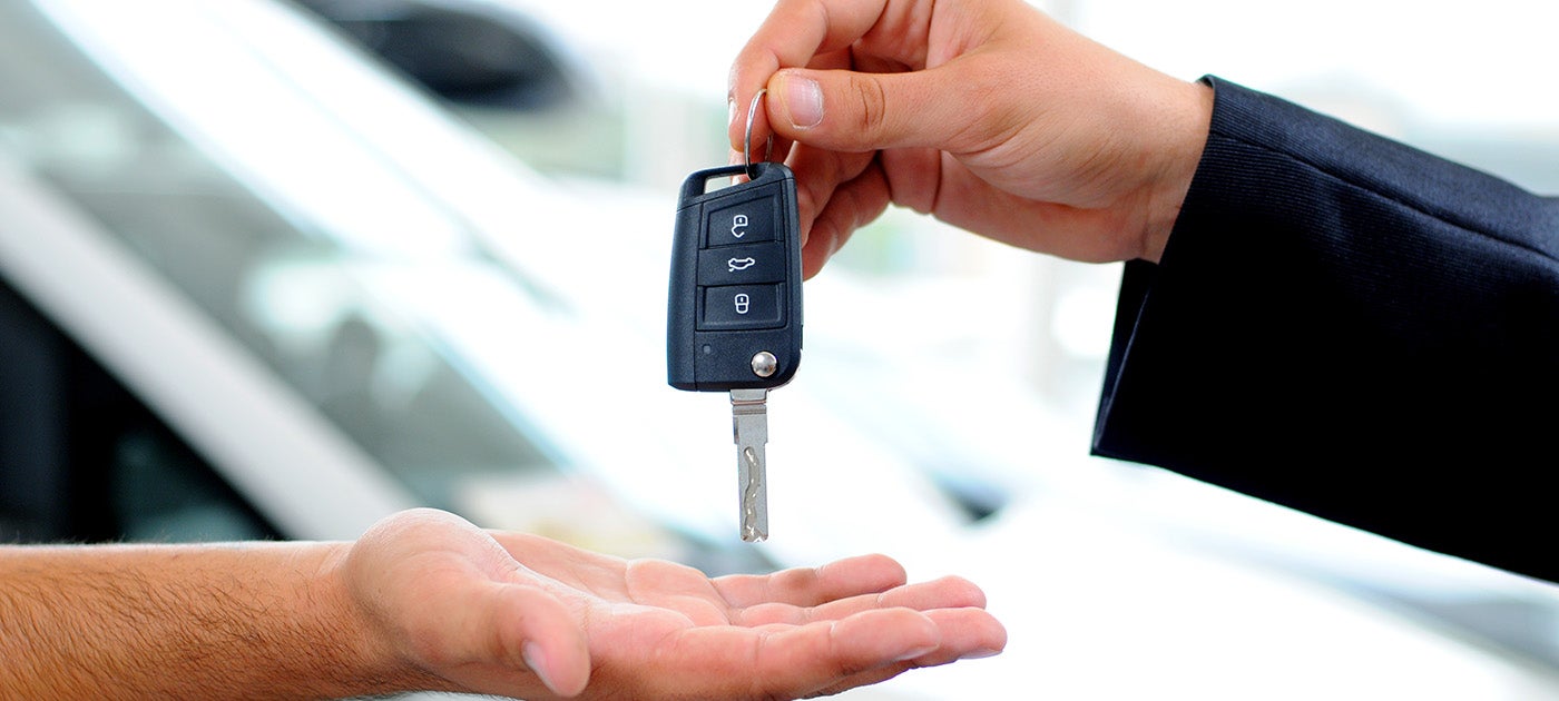 A car salesman passing a key to a customer