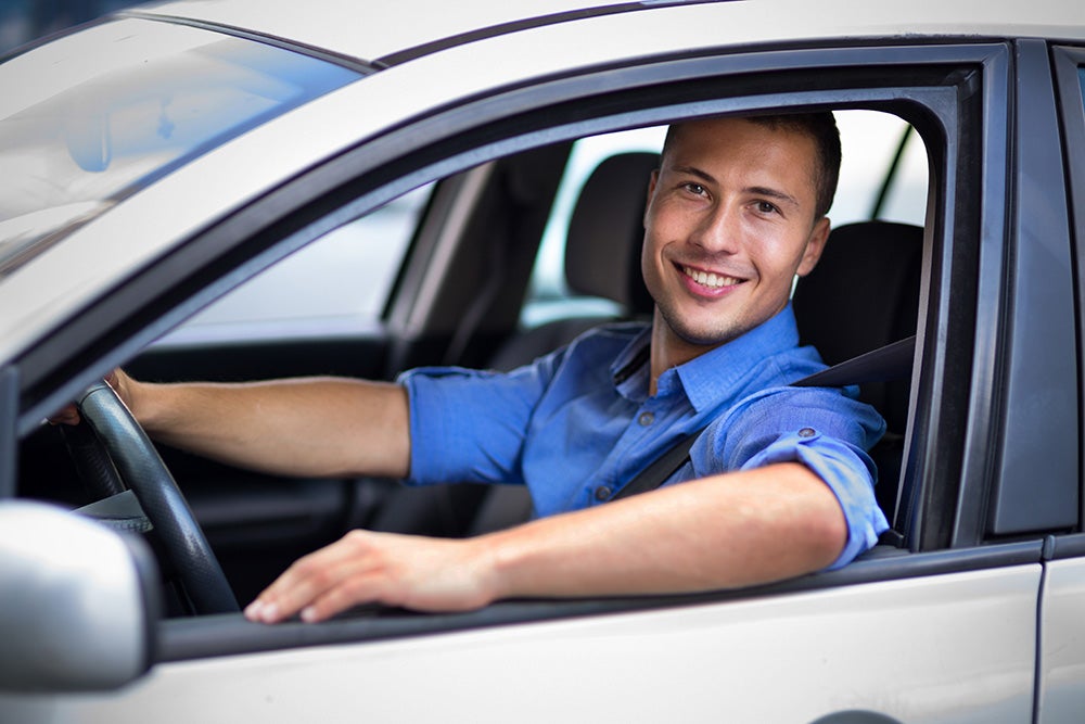 A man smiling and leaning out of a car window
