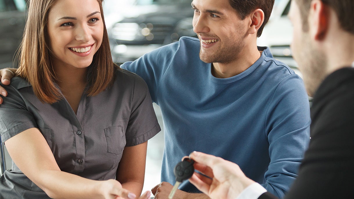 A man and woman meeting with a finance professional at a dealership