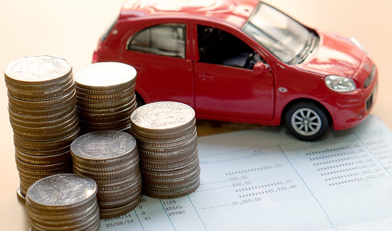A stack of coins in front of a model car