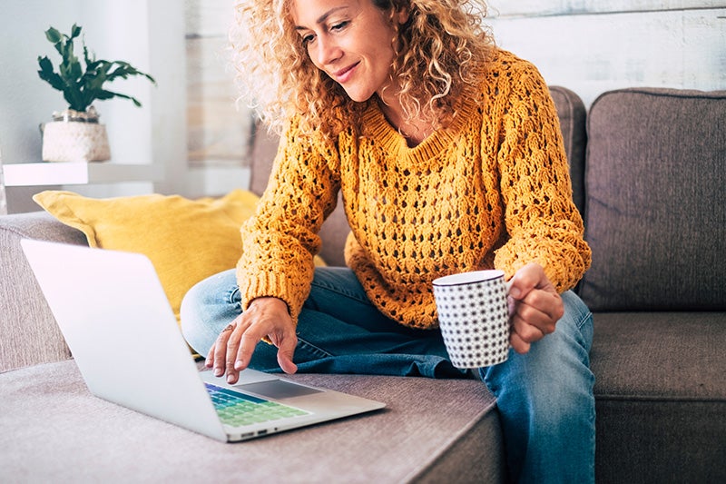 A woman drinking coffee and shopping for a car online