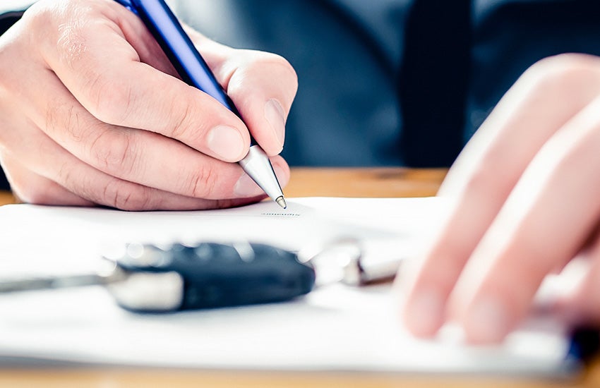 A person signing a contract for a car purchase
